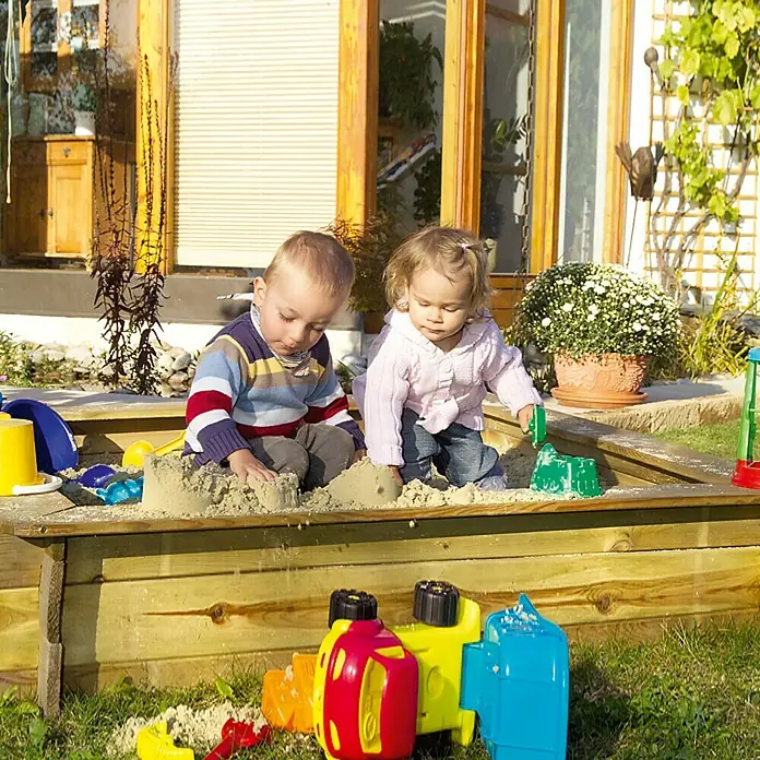 Min2C Kinderspielsand Hund- und Katzenabweisend - 25 kg - Zwei Kinder spielen in einem Sandkasten aus Holz mit buntem Spielzeug. Sie haben Spaß beim Spielen im Freien.