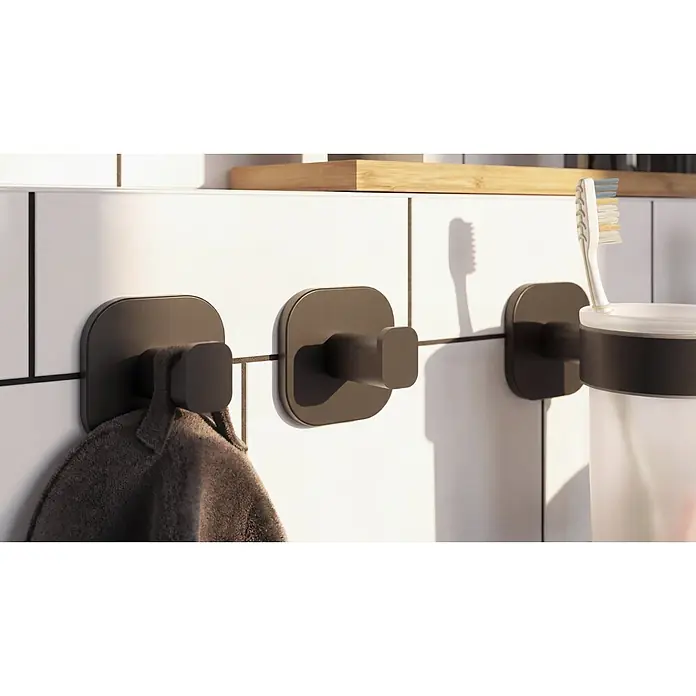 Venus Handtuchhaken Prag - Schwarz, Matt - Mattschwarze wandmontierte Haken und Zahnbürstenhalter, mit dunklem Handtuch und Zahnbürste.