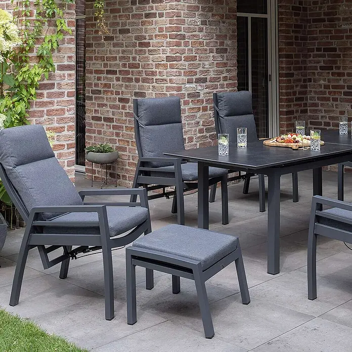 Bene Living Gartentisch-Set Merida + Hocker mit Tisch Granada - Gesamtumfang: 9 -tlg., Aluminium pulverbeschichtet, Textilene, Keramik, Ausziehbar - Graues Gartenmöbel-Set mit Tisch, Stühlen, Liegesessel und Hocker auf einer Terrasse.