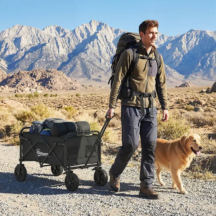 Outsunny Bollerwagen - L x B x H: 85 x 50 x 99 cm, Traglast: 80 kg, Metall - Schwarzer Faltwagen, gefüllt mit Campingausrüstung, von einer Person auf einem Schotterweg in Naturlandschaft gezogen.