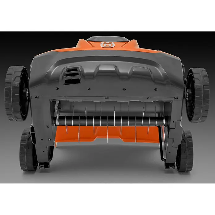 Husqvarna Elektro-Vertikutierer - 1,6 kW, Arbeitsbreite: 37,5 cm - Unterseite eines orange-grauen Robotermähers mit großen Rädern und einer Vertikutierwalze mit Metallzinken.