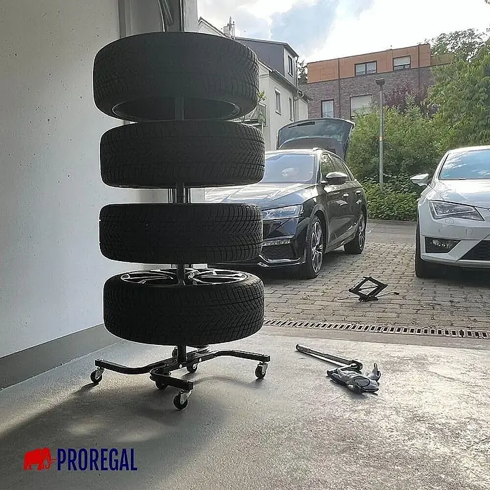 Proregal Reifenregal Fahrbarer Felgenbaum CARRERO - Stecken, Schwarz - Schwarzer mobiler Reifenständer auf Rollen, der vier Reifen in einer Garagenumgebung hält.