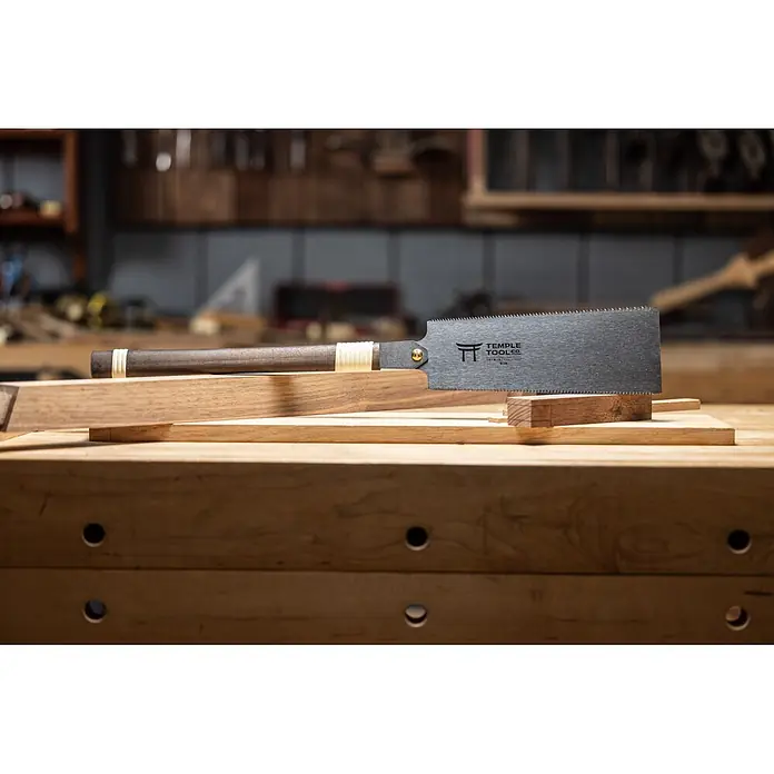 Temple Tool Japansäge Ryoba - Blattlänge: 240 mm - Japanische Zugsäge mit dunklem Holzgriff und Metallklinge, auf Holzbrettern auf einer Werkbank, bereit für Holzarbeiten.