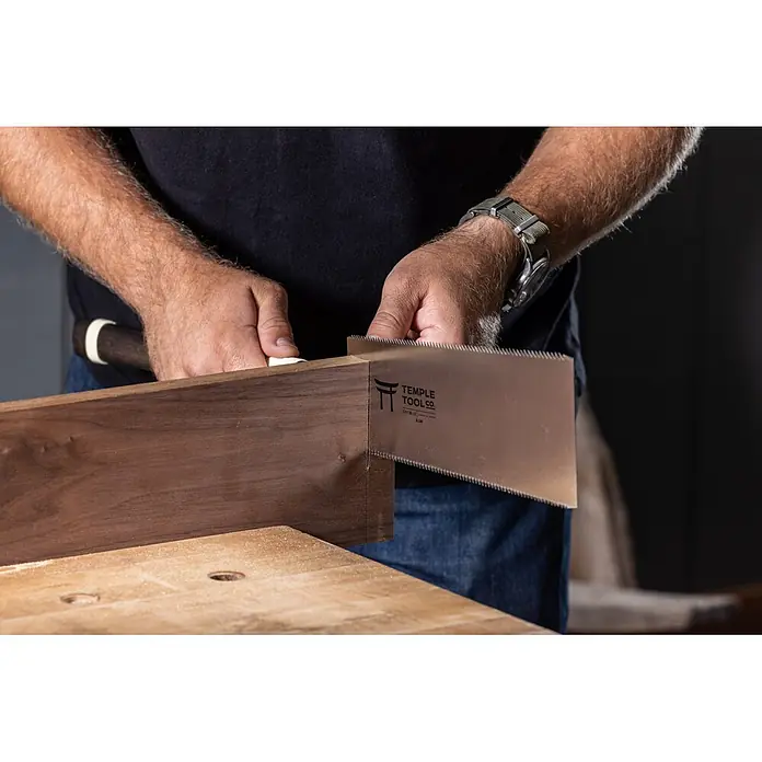 Temple Tool Japansäge Ryoba - Blattlänge: 240 mm - Hände benutzen eine japanische Zugsäge von Temple Tool Co. mit Metallblatt, um dunkles Holz auf einer Werkbank zu schneiden.