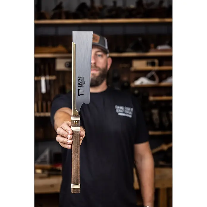 Temple Tool Japansäge Dozuki Cross Cut - Blattlänge: 240 mm - Eine Person hält eine japanische Zugsäge mit Messingrücken und dunklem Holzgriff, bereit für die Holzbearbeitung.