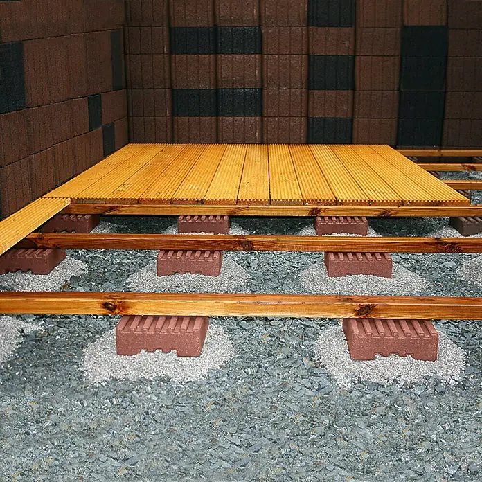 Christoph Fundamentstein - 22 x 22 x 8 cm, Beton - Holzterrasse im Bau mit Unterkonstruktion und Steinplatten auf Kiesbett. Stufenweise Anleitung zum Terrassenbau im Garten.