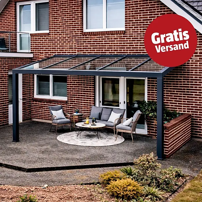Gardendreams Terrassenüberdachung Elegance - B x T: 400 x 305,5 cm, Anthrazitgrau, Verbundsicherheitsglas (VSG), Klar - Dunkelgraue Terrassenüberdachung mit Glasdach über einer möblierten Terrasse vor einem Backsteinhaus.