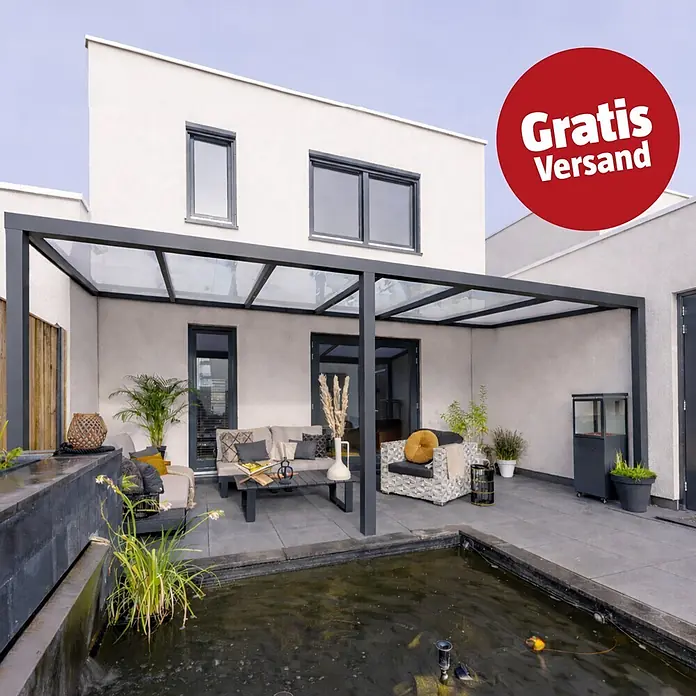 Gardendreams Terrassenüberdachung Essence - B x T: 600 x 255,5 cm, Anthrazitgrau, Verbundsicherheitsglas (VSG), Klar - Moderne dunkelgraue Metall- und Glaspergola über einer Terrasse mit Gartenmöbeln an einem weißen Haus. Roter 'Gratis Versand' Aufkleber.