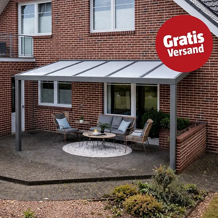 Gardendreams Terrassenüberdachung Elegance - B x T: 400 x 355,5 cm, Graualuminium, Polycarbonat, Opal - Moderner grauer Terrassenüberdachung mit lichtdurchlässigem Dach an einem roten Backsteinhaus, der einen Sitzbereich im Freien überdacht.