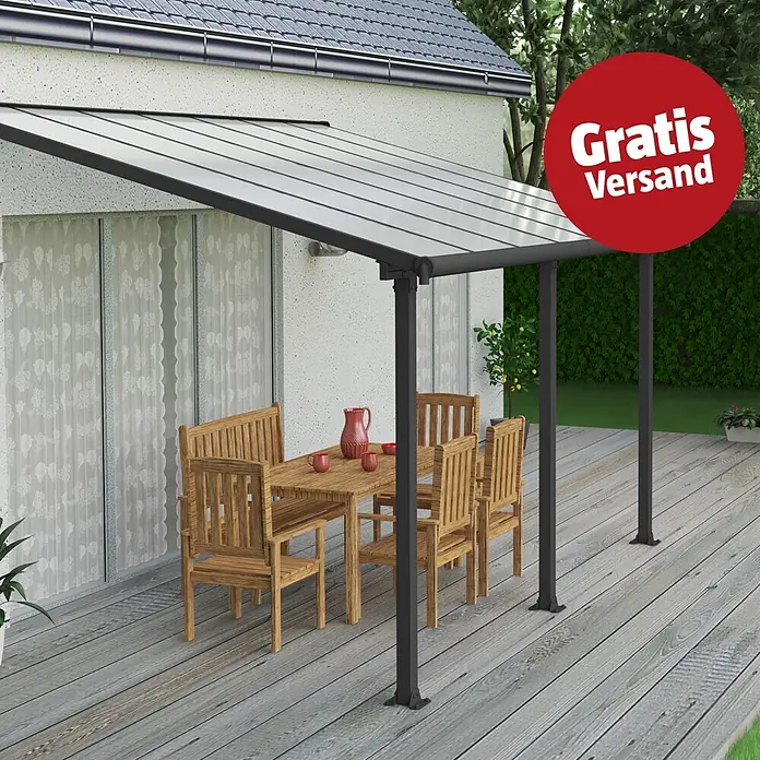 Palram – Canopia Terrassenüberdachung Olympia - B x T: 425 x 300 cm, Anthrazitgrau, Polycarbonat, Transparent - Eine moderne, dunkelgraue Terrassenüberdachung mit lichtdurchlässigem Dach schützt eine Holz-Sitzgruppe auf einer Holzterrasse am Haus.