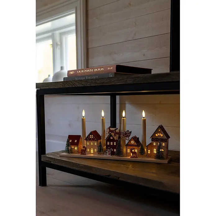 Konstsmide LED-Holzsilhouette Miniaturhäuser - 47 x 11 x 20,5 cm, Braun, Batteriebetrieben, Warmweiß - Adventsleuchter aus Holz in Form eines Weihnachtsdorfes mit vier LED-Kerzen, beleuchteten Häusern und kleinen Figuren.