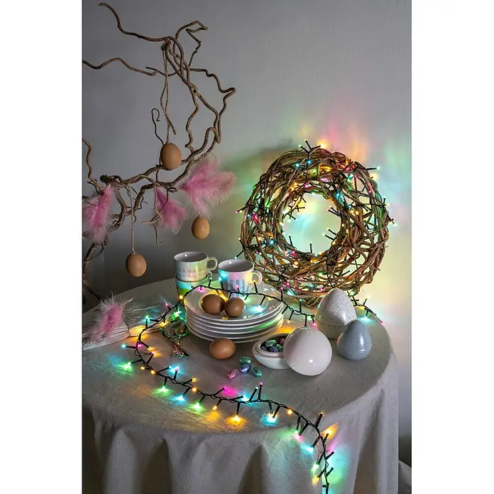 Konstsmide LED-Clusterlichterkette Pastell - Außen, Länge: 8,78 cm, 400 Stk., Netzbetrieben - Bunte Lichterkette beleuchtet einen festlichen Ostertisch mit Ästen, Eiern und einem Kranz.