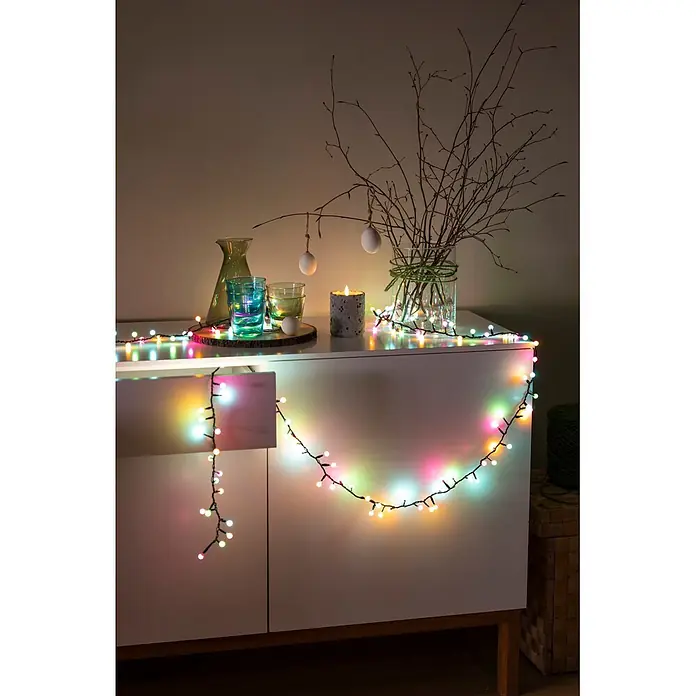 Konstsmide LED-Clusterlichterkette Globe Pastell - Außen, Länge: 8,78 cm, Netzbetrieben - Bunte Lichterkette über einem weißen Schrank, beleuchtet Osterdekorationen.