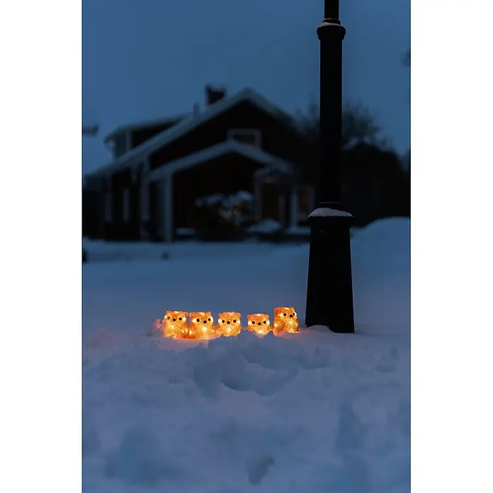 Konstsmide LED-Dekofigur - Außen, Lichtfarbe: Warmweiß, Anzahl Leuchtmittel: 40 Stk., Netzbetrieben - Fünf leuchtende orange Eulenfiguren im tiefen Schnee, die ein warmes Licht in einer dunklen, winterlichen Außenszene werfen.