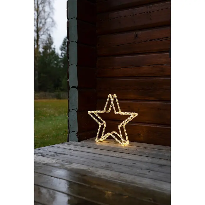 Konstsmide LED-Stern - 40 cm, Lichtfarbe: Warmweiß, IP44, Netzbetrieben - Leuchtende Sternendekoration mit klaren Perlen auf einer Holzveranda vor einer Blockhütte.