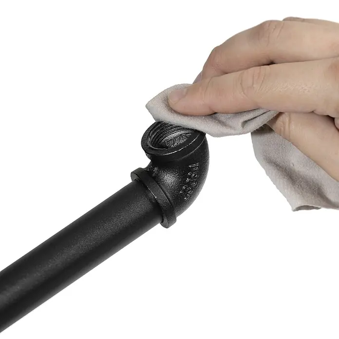 Walteco Rusticline Anti-Rutsch-Pad RT-62, Ø34mm,12STK - Durchmesser: 34 mm, Schwarz, Kleben, 12 Stk. - Hand wischt ein schwarzes Metallrohr-Winkelstück mit einem hellen Tuch ab.