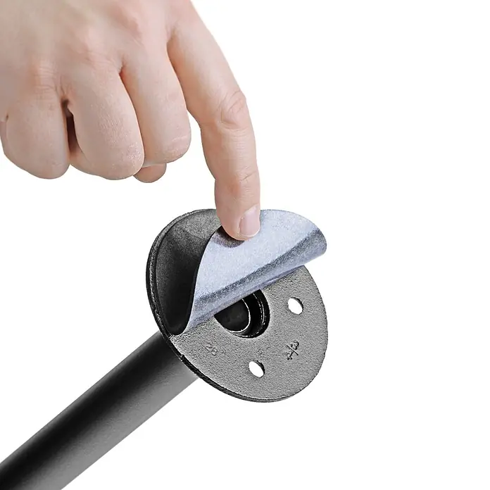 Walteco Rusticline Anti-Rutsch-Pad RT-61, Ø83mm,4STK - Durchmesser: 83 mm, Schwarz, Kleben, 4 Stk. - Hand zieht eine Filzschutzfolie von einem schwarzen Industrierohrflansch ab, der an einem Rohr befestigt ist.