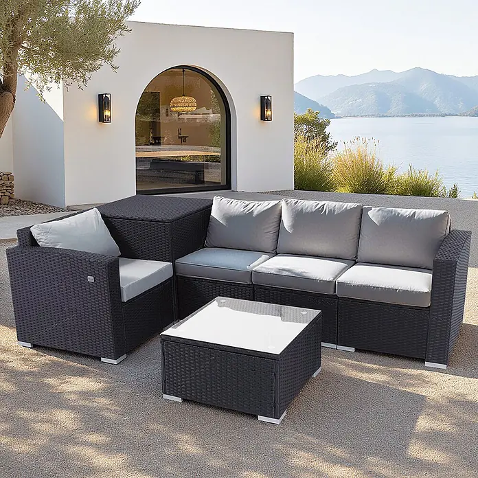 HOMAVO Loungemöbel-Set - 3 -tlg., Polyester und pulverbeschichteter Stahlrahmen, Schwarz-Grau - Dunkelgraues Rattan-Lounge-Set mit hellgrauen Kissen und passendem Couchtisch auf einer Terrasse am See.