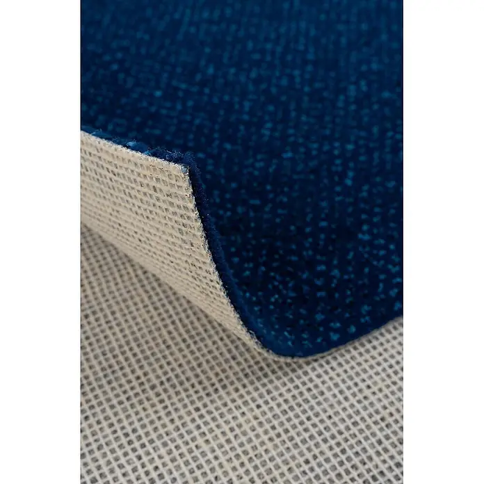 Bricoflor Teppichboden Meterware 4,5x4m, Velours gemustert, dunkel-blau blau - Velours, 100 % Polyamid (PA), dunkel-blau blau - Dunkelblauer, texturierter Teppich, teilweise angehoben, zeigt seine beige, gittergemusterte Anti-Rutsch-Rückseite.