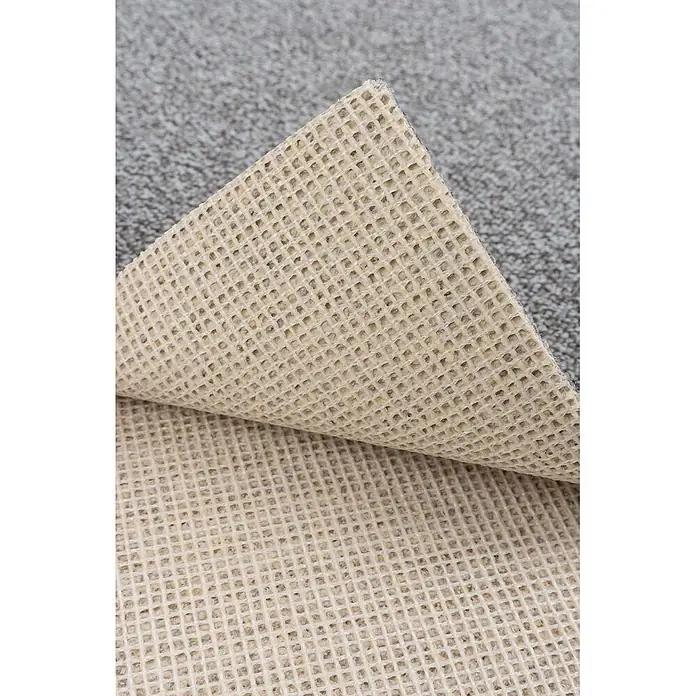 Bricoflor Teppichboden Meterware 2x4m, Schlinge meliert, hell-grau silber - Schlinge, 100 % Polyamid (PA), hell-grau silber - Helle beige Waffelmuster-Antirutschunterlage, teilweise von grauem Teppich abgehoben.