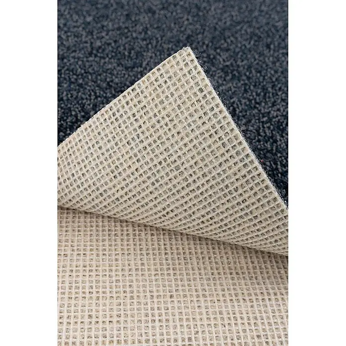 Bricoflor Teppichboden Meterware 2,5x4m, Schlinge meliert, dunkel-blau - Schlinge, 100 % Polyamid (PA), dunkel-blau - Nahaufnahme eines dunkelblauen Teppichs, teilweise angehoben, zeigt seine beige, rutschfeste Gitterunterseite, die Verrutschen verhindert.