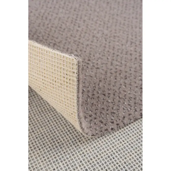 Bricoflor Teppichboden Meterware 6,5x4m, Velours gemustert, grau beige - Velours, 100 % Polyamid (PA), grau beige - Nahaufnahme eines grauen Teppichs mit beige-wabenförmiger Antirutsch-Rückseite, auf einer gerasterten Unterlage liegend.