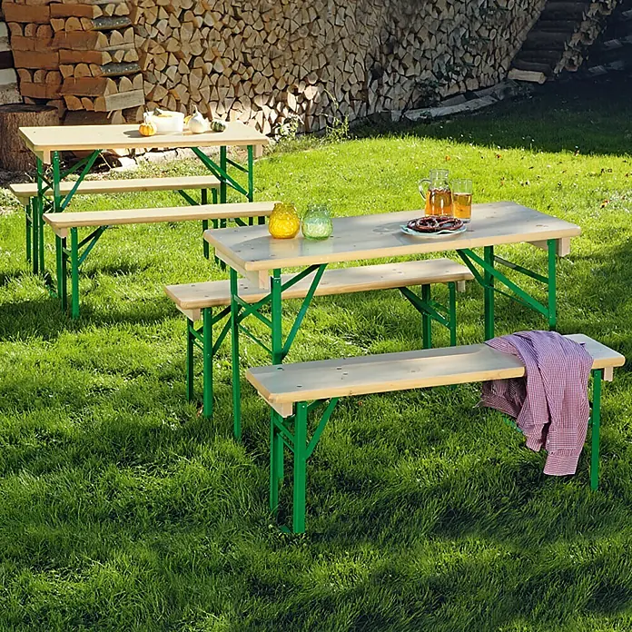 Sunfun Bierzeltgarnitur - 3 -tlg., Nadelholz/Stahl, Klappbar, Naturbraun/Grün, Tisch (L x B x H): 110 x 50 x 77 cm, Bank (B x T x H): 110 x 25 x 49 cm, Ohne Rückenlehne - Zwei Biergartengarnituren mit Holztischen und grünen Beinen stehen auf einer grünen Wiese, ideal für Gartenpartys.