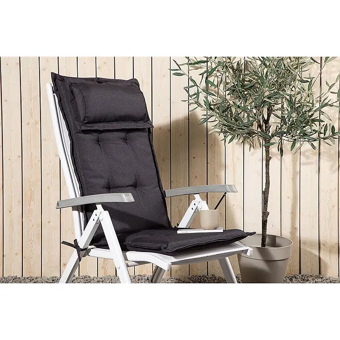 Ebuy24 Sitzauflage Cus - 1 Stk., L x B x H: 46 x 116 x 6 cm, Fasern, Schaum, Polyester., Grau - Dunkelgraues Outdoor-Stuhlkissen auf einem weißen Gartenliegestuhl vor Holzzaun und Olivenbaum.