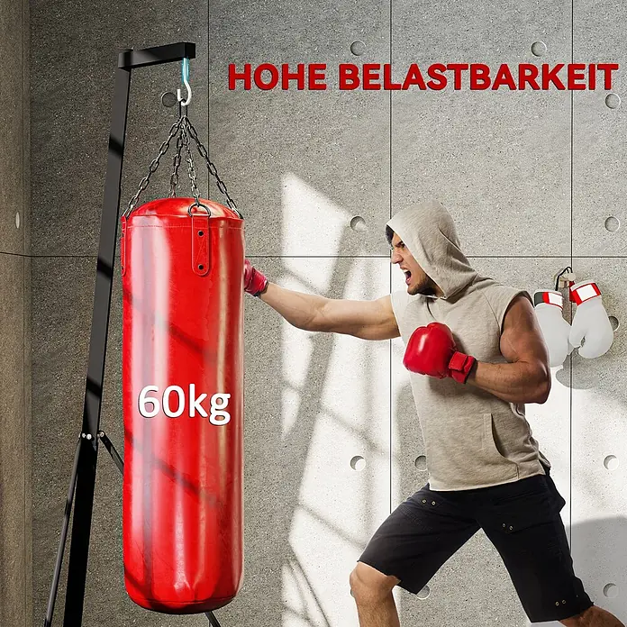 Sportnow Boxsack Ständer - Schwarz - Ein roter 60kg Sandsack an einem Ständer wird von einem Mann mit roten Boxhandschuhen geschlagen. Weiße Boxhandschuhe hängen an der Wand.