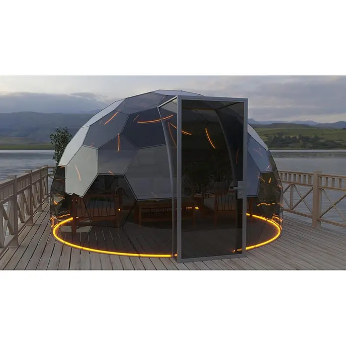 BubbleOrb Gartenkuppel - Durchmesser: 400 cm, Bronze - Glaskuppel mit dunklen Rahmen und orangefarbener LED-Basis auf einem Holzsteg am See, mit Sitzgelegenheiten innen.