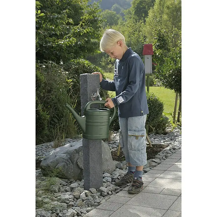 Arves Wasserzapfstelle Natura - Black Granitfarben, Höhe: 98 cm - Ein Junge füllt eine grüne Gießkanne an einem Wasserhahn im Garten.