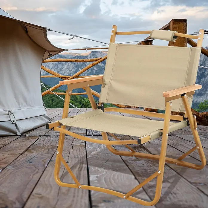SVITA Campingstuhl - Beige, B x T x H: 55 x 53 x 61 cm - Beige klappbarer Campingstuhl mit Holzarmlehnen auf einer Holzterrasse neben einem Zelt mit Bergblick.