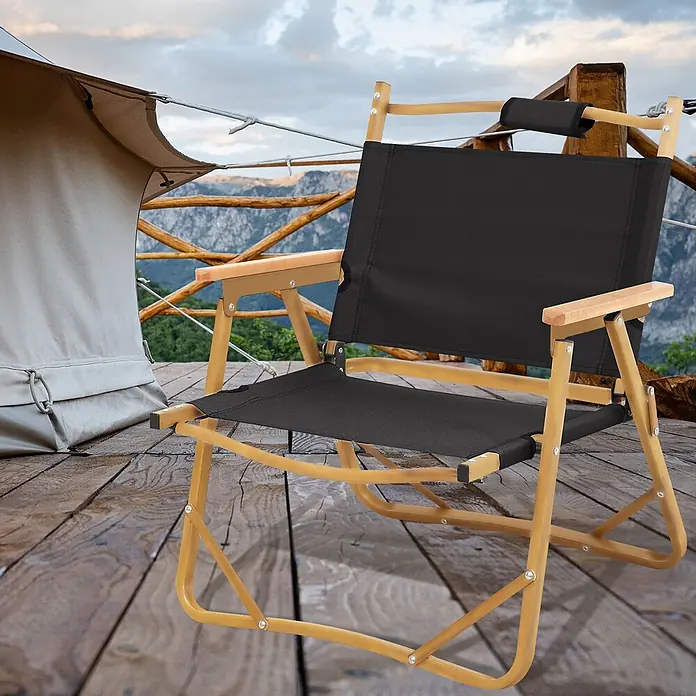 SVITA Campingstuhl - 1 Stk., Aluminium in Holzoptik, Klappbar, Schwarz, B x T x H: 55 x 53 x 61 cm - Schwarzer Campingstuhl mit hellem Holzrahmen, auf einer Holzterrasse im Freien neben einem Zelt platziert.