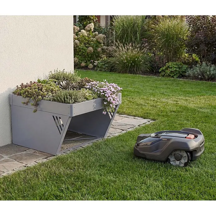 Proregal Mähroboter-Garage Mit Pflanzkasten - L x B x H: 70 x 60 x 40 cm, Grau, Ausführungseigenschaft: mit Pultdach, Gardena, WORX, Husqvarna, Einhell, Landxcape, Juka - Grauer Metall-Pflanzkasten als Mähroboter-Unterstand, bepflanzt, mit Mähroboter auf Rasen.