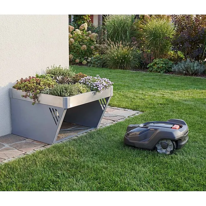 Proregal Mähroboter-Garage Mit Pflanzkasten - Grau, Ausführungseigenschaft: mit Pultdach, Gardena, WORX, Husqvarna, Einhell, Landxcape, Juka - Graue Metallgarage für Mähroboter mit Sukkulenten-Pflanzdach, im Garten neben einem Mähroboter.