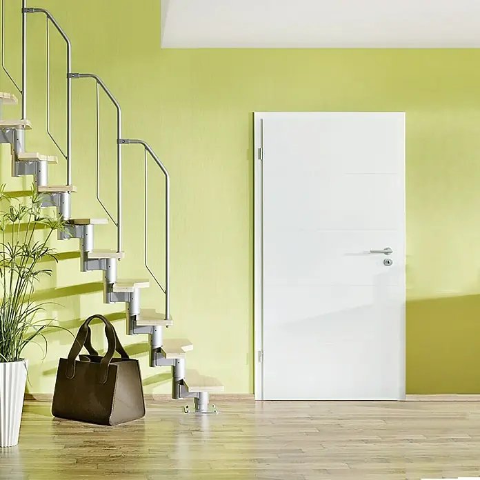 Star Stairs Raumspartreppe Athena - Geschosshöhe: 222 cm - 276 cm, Anzahl Steigungen: 11 Stk. - Eine moderne Raumansicht mit einer freitragenden Treppe und einer eleganten, weißen Tür. Die Treppe mit Metallgeländer und hellen Stufen passt zum Interieur.