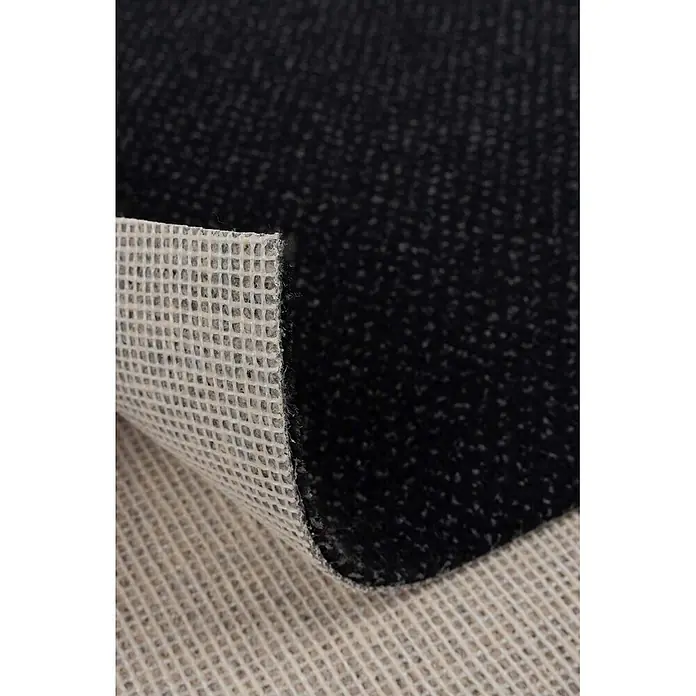 Bricoflor Teppichboden Meterware 7,5x4m, Velours gemustert, anthrazit schwarz - Velours, 100 % Polyamid (PA), anthrazit schwarz - Nahaufnahme eines schwarzen Teppichs mit texturiertem Flor und heller Gitter-Antirutschunterseite.