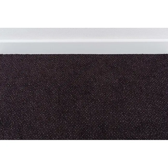Bricoflor Teppichboden Meterware 8,5x4m, Velours gemustert, anthrazit violett - Velours, 100 % Polyamid (PA), anthrazit violett - Dunkelbrauner, strukturierter Teppich mit hellen Sprenkeln, angrenzend an eine weiße Fußleiste.