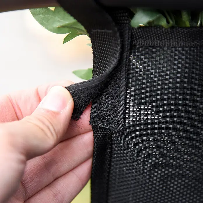 Outsunny Garten-Schaukelstuhl - 1 Stk., Metall, atmungsaktives Mesh, Schwarz - Hand löst einen schwarzen Klettverschlussriemen von einem gewebten schwarzen Netzpanel.