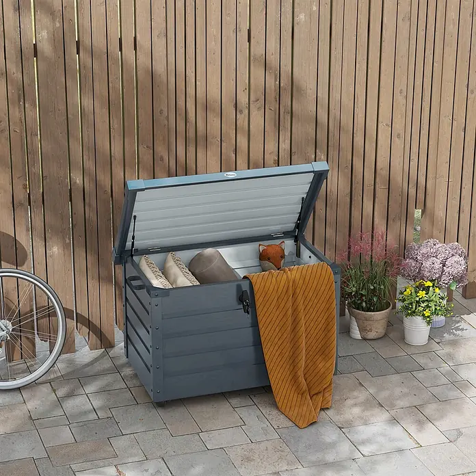 Outsunny Garten-Aufbewahrungsbox - Dunkelgrau, Stahl - Dunkelgraue Outdoor-Aufbewahrungsbox mit hellgrauem Deckel, teilweise offen, mit Kissen und Fuchs-Spielzeug. Eine gelbe Decke hängt über der Seite.