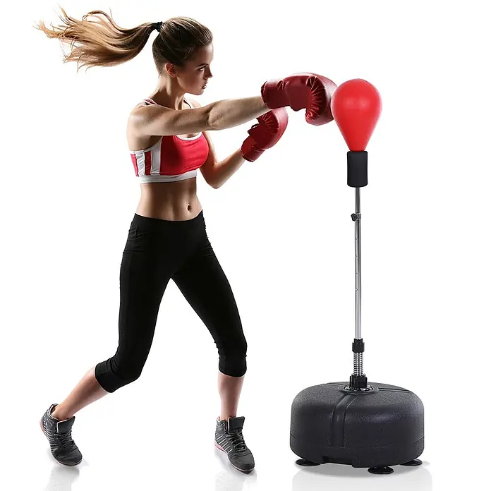 Homcom Boxsack - Ø x L: 48 x 48 cm, Schwarz, Rot - Eine Frau in Boxhandschuhen schlägt einen roten freistehenden Boxsack mit schwarzem Sockel.