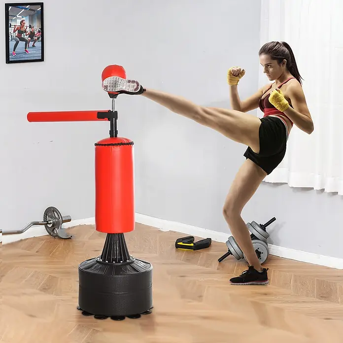 Homcom Boxsack - Ø x L: 48 x 88 cm, Schwarz, Rot - Frau tritt roten & schwarzen freistehenden Boxsack mit Federaufsatz und horizontaler Stange im Heim-Fitnessstudio.