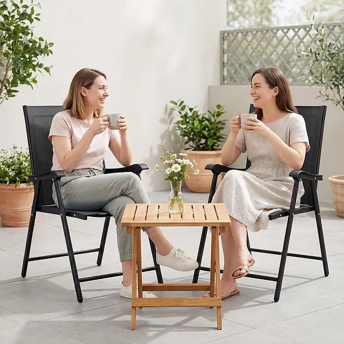 Outsunny Gartenstuhl-Set - 2 Stk., Stahl, Texteline, Klappbar, Schwarz - Zwei schwarze Klappgartenstühle und ein kleiner Holztisch auf einer Terrasse, für entspannte Stunden im Freien.