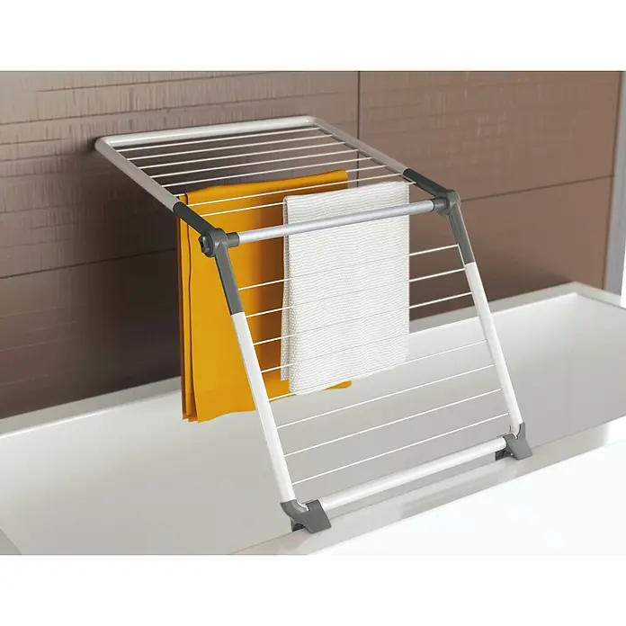 Juwel Stand-Wäscheständer SuperDry Wing - Länge Wäscheleine: 8,8 m, L x B x H: 103,1 x 60,1 x 7,1 cm, Weiß/Obsidian Grey - Silber-grauer Metall-Wäscheständer über einem weißen Waschbecken mit orangefarbenem und weißem Handtuch.