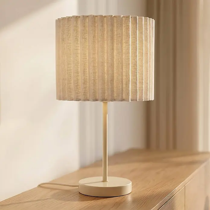 Lindby Tischleuchte Libbie - L x B x H: 25 x 25 x 45 cm, creme / amber, E27 - Hellbeige Tischlampe mit plissiertem Stoffschirm auf einer Holzfläche, warm leuchtend.