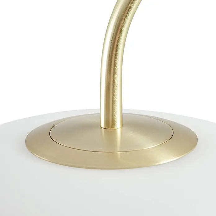 Lucande Stehleuchte Tenebra - messing / gold, weiß / opal - Nahaufnahme eines gebürsteten Messing-Lampenarms, der mit einem runden Sockel auf einer weißen Oberfläche verbunden ist.