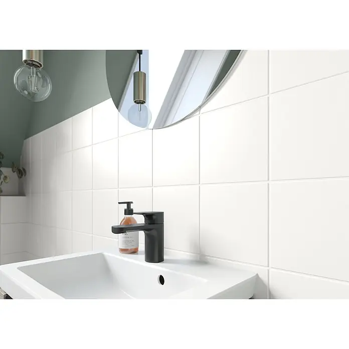 Alpina Weißlack Bad & Küche 3 in 1 Fliesenlack (Weiß) - Weiß, Seidenglänzend, 500 l, Lösemittelbasiert - Ein schwarzer Wasserhahn und ein Seifenspender auf einem weißen Waschbecken.