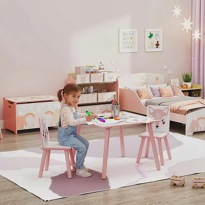 Zonekiz Kindertisch Rosa 60cm x 60cm x 44cm -  - Ein Kind zeichnet an einem rosa Spieltisch mit zwei Stühlen, einer mit Fuchskopf, in einem rosa Kinderzimmer mit Bett und Spielzeugaufbewahrung.