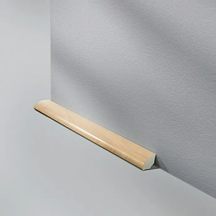LOGOCLIC Viertelstab Buche Hell - 250 cm x 14 mm x 14 mm - Nahaufnahme einer hellen, hölzernen Viertelstab-Fußleiste, die an einer grau gestrichenen Wand angebracht ist und einen sauberen Übergang schafft.