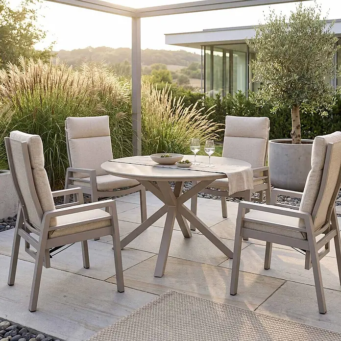 Bene Living Gartentisch-Set Sevilla Malaga Ivory - Gesamtumfang: 5 -tlg., Aluminium pulverbeschichtet, Textilene, Keramik, Ausziehbar - Modernes Outdoor-Essgruppe: runder Tisch mit sternförmigem Untergestell und vier Stühlen mit hellen Kissen auf einer Terrasse.